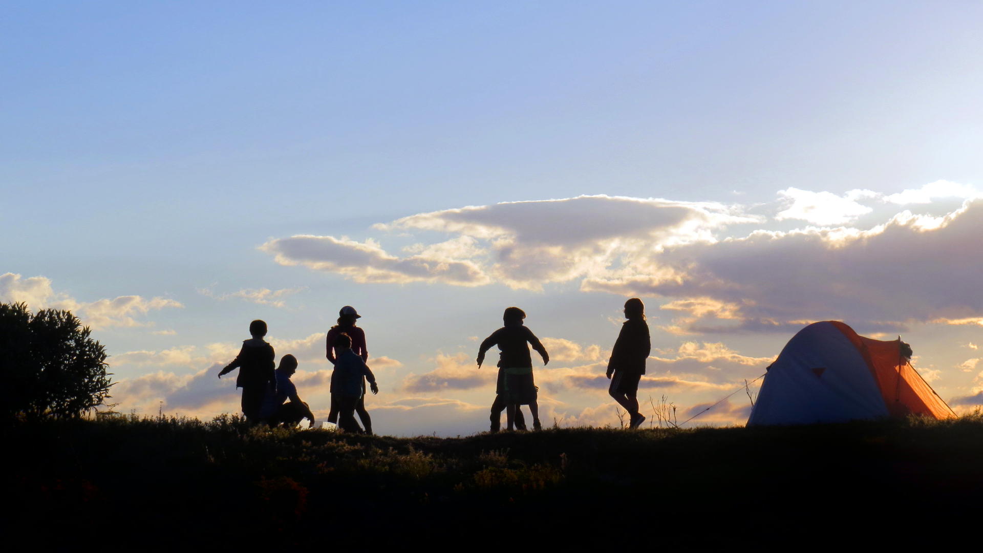 Crianças correndo no acampamento ao por do sol.